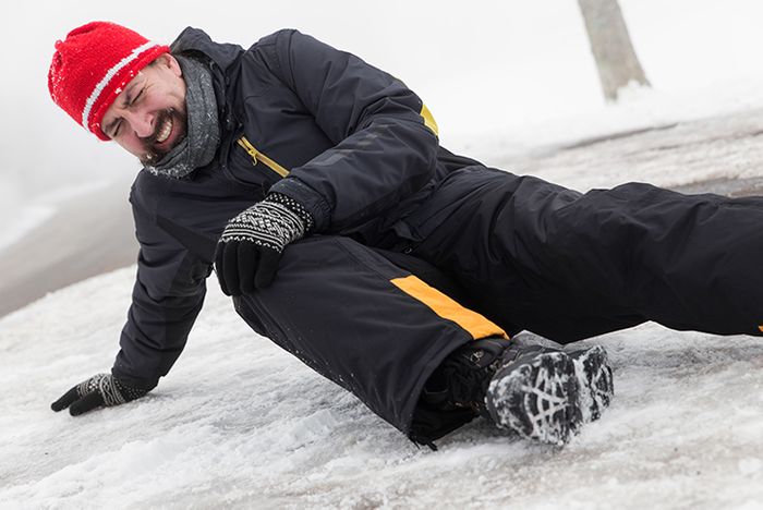 A man laying on the ice holding his knee