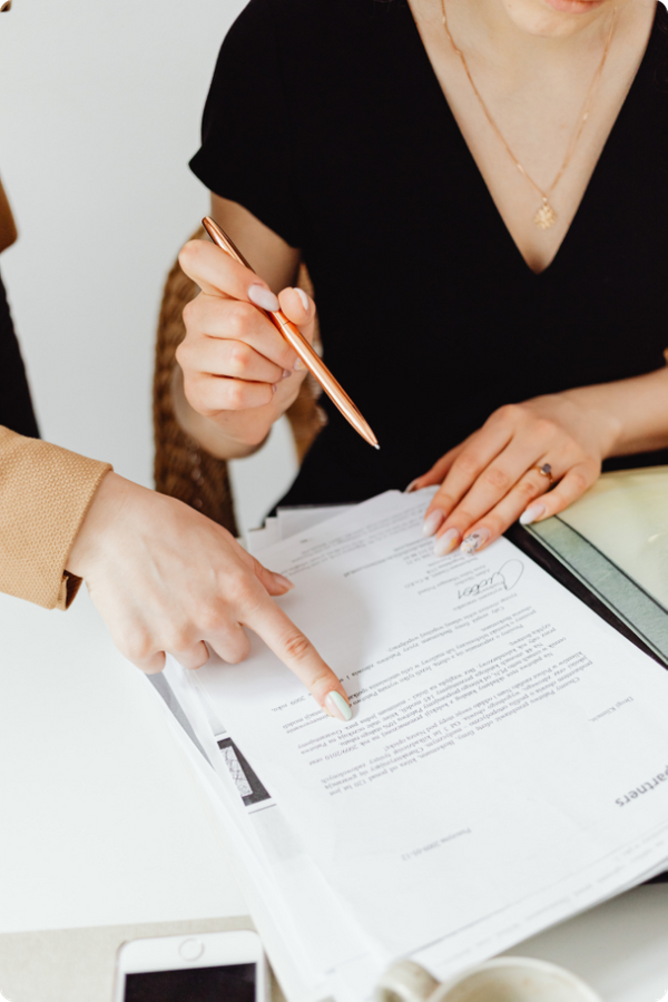 A close-up shot of an advisor pointing to a specific clause on a legal document while a client holds a pen, ready to sign.