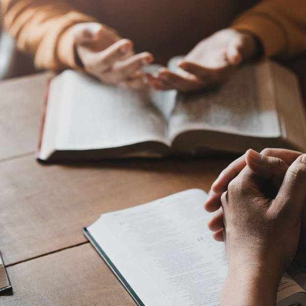 Two people's hands over bibles