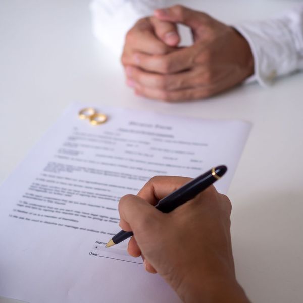 Person signs annulment papers in front of mediator with two rings on the paper