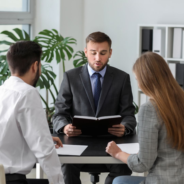 a person looking at their paperwork and talking to a couple