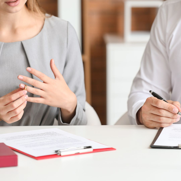 Man and woman sign annulment papers while wife takes off her ring.