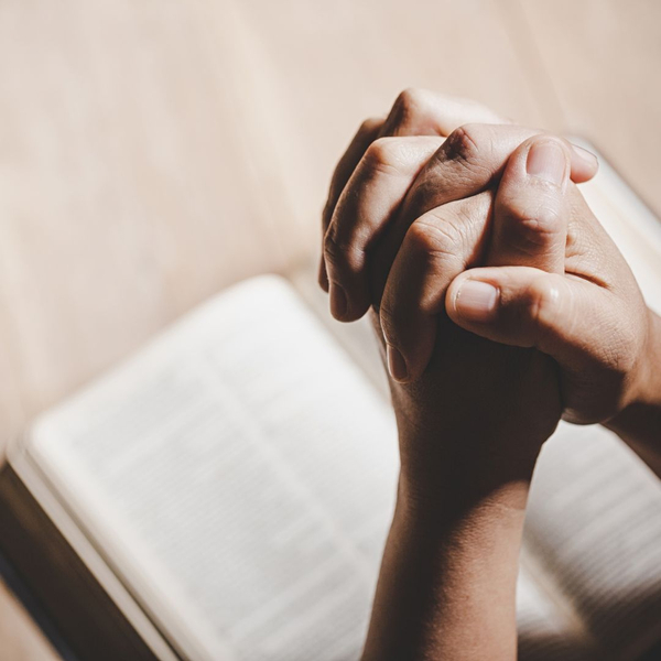 praying hands over Bible