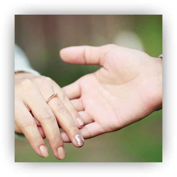 Holding hands wearing engagement rings