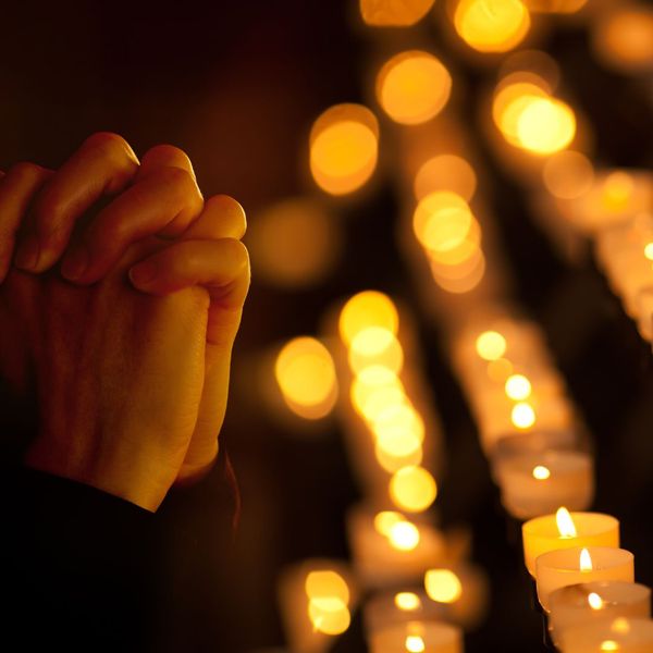 praying hands near candles