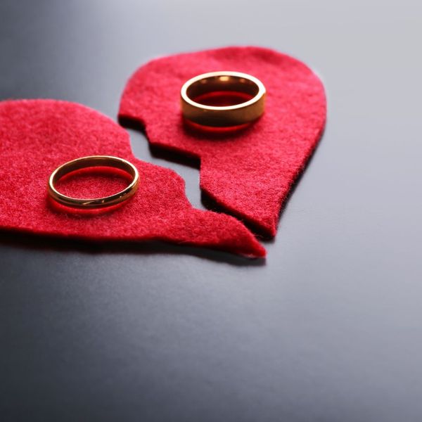Two wedding bands sit on each half of a broken heart