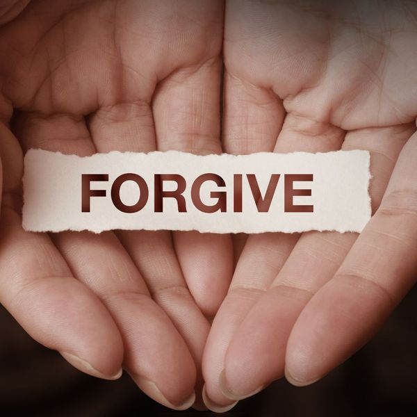 person holding a paper that says forgive