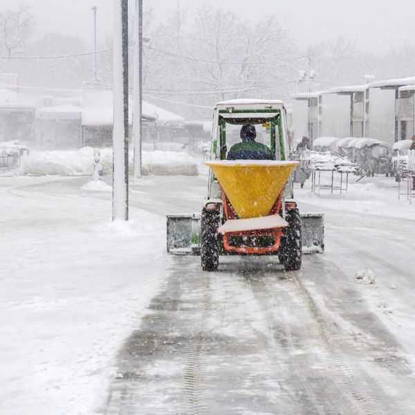 machine spreading rock salt while it's snowing