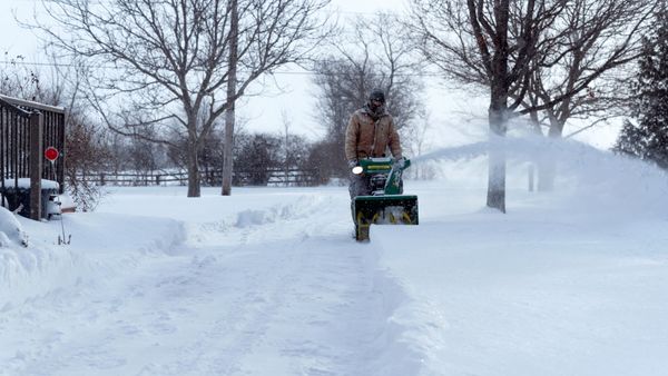 person running a snow blower to remove snow