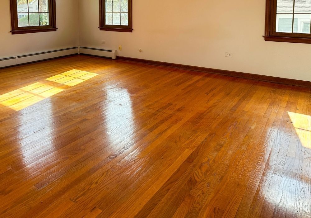 Warm, glossy hardwood flooring restored to pristine condition inside a bright residential living space