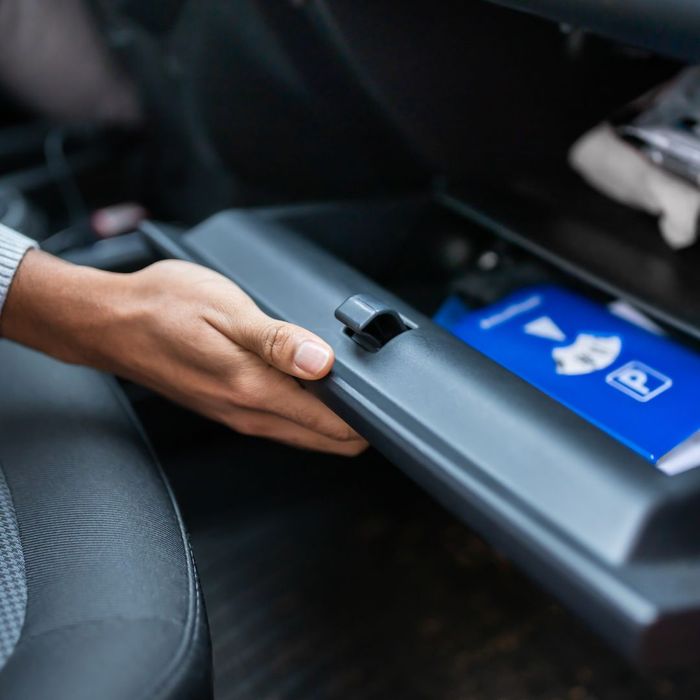 Person opening glovebox to get car's owner's manual