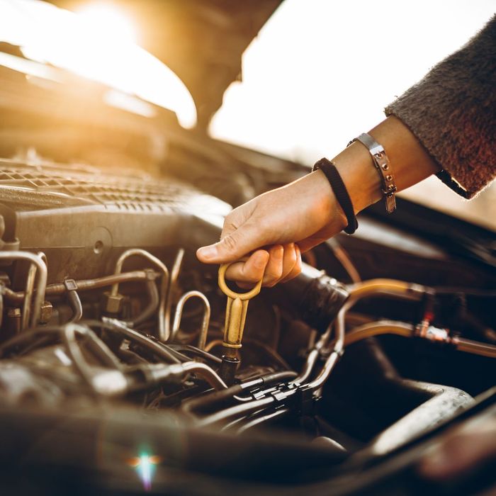 A person grabbing the dipstick to check their car engine's oil level