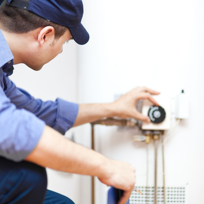 An image of a man adjusting a water heater. An image of a man adjusting a water heater.