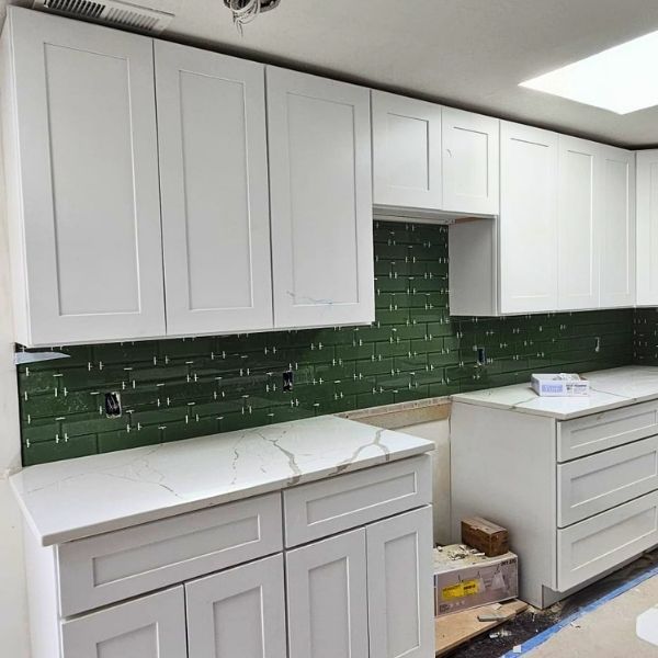 remodeled kitchen with white cabinets and green backplash