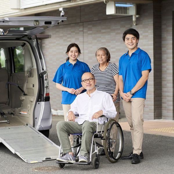 Three people standing behind a man next to a medical transport van. 