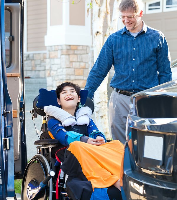 Icon of a man standing next to a kid in a wheel chair