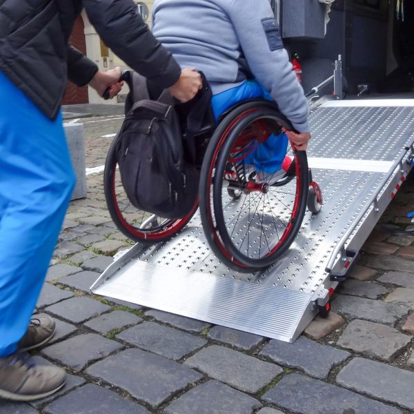 pushing a wheelchair up a ramp on a van
