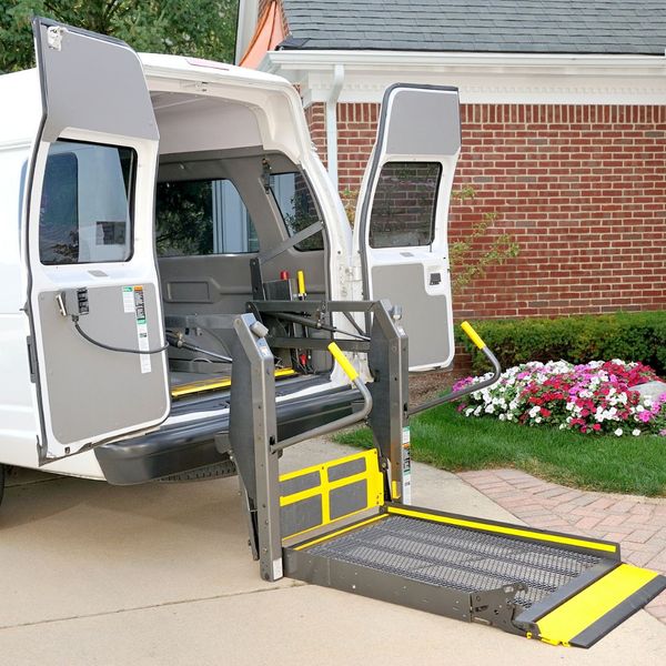 The back of a wheelchair van open with a ramp coming out the back. 