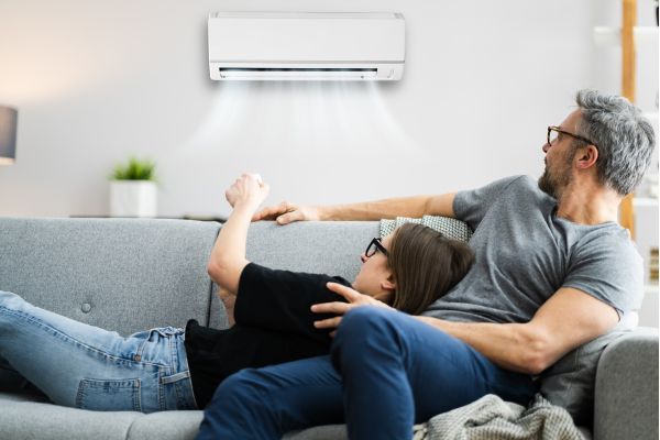 two people relaxing on the couch turning on a wall ac unit