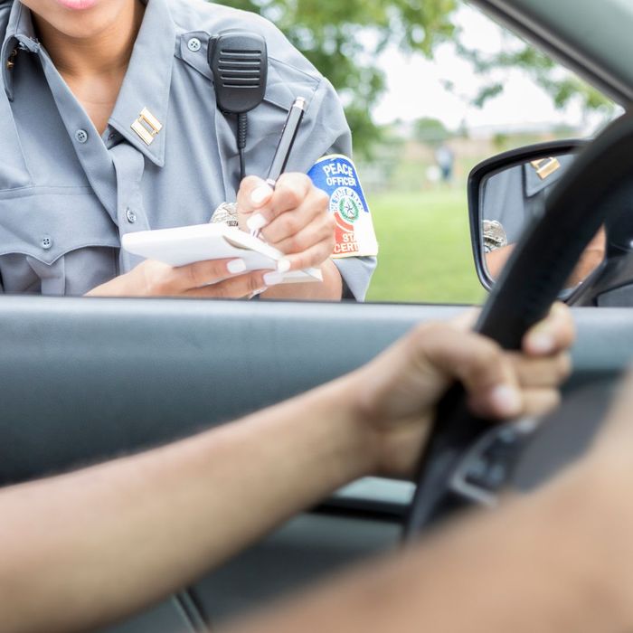 Person gripping the steering wheel while a police office writes them a ticket. 