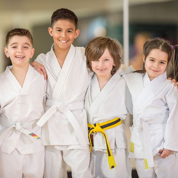 group of kids in karate uniforms with arms around eachother