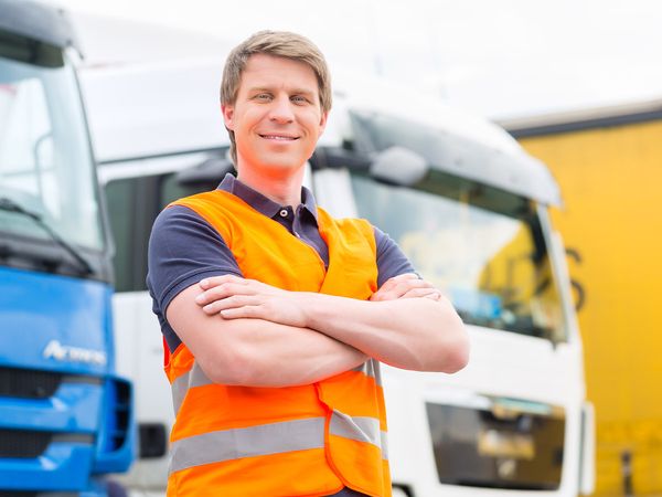 a happy worker in front of a semi truck