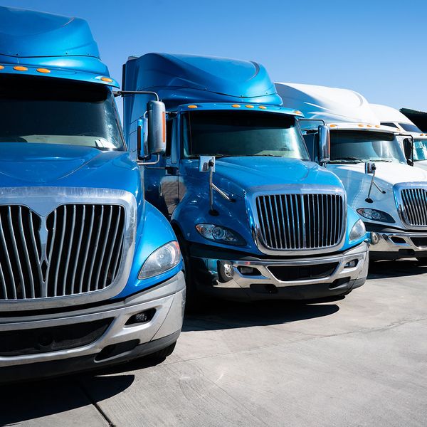 Semi-truck fleet parked next to one another in a long line.