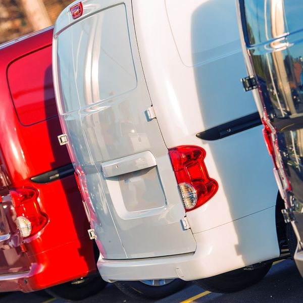 Various colored fleet vans parked side by side in parking spaces.