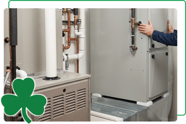 An interior photograph within a clean utility room, showing two technicians carefully guiding a new, high-efficiency furnace cabinet into place as part of a professional HVAC upgrade in a Windsor home.
