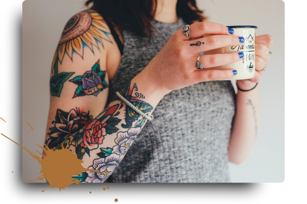 woman with tattooed arms holding mug