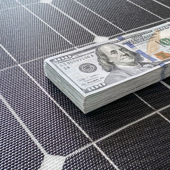 stack of cash on top of solar panels