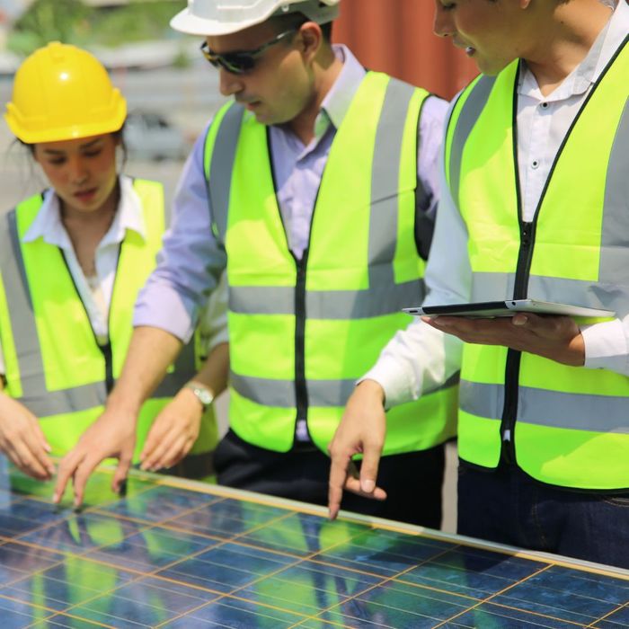 workers in safety gear inspecting a solar panel