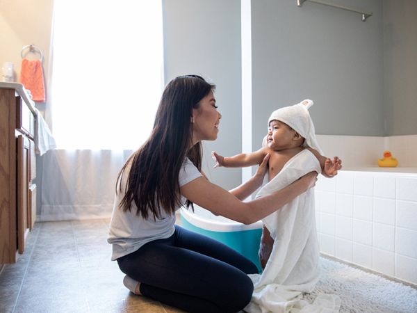 Mother drying off her young child after a bath