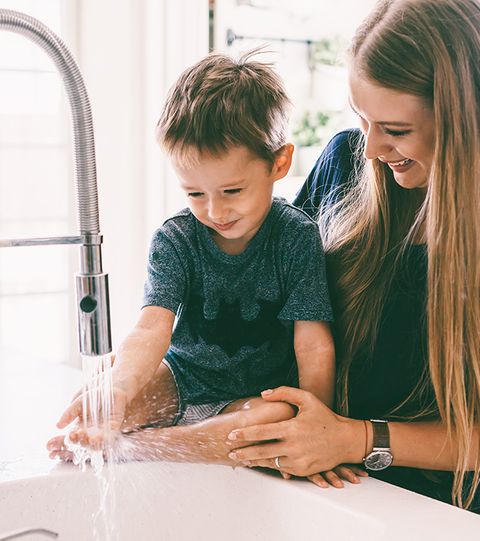 Mother and son using kitchen sink