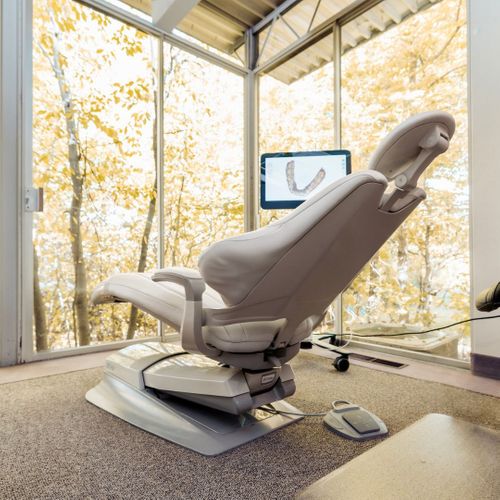 Dentist chair in room with windows.