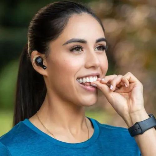 Woman wearing headphones putting invisible teeth aligners in. 