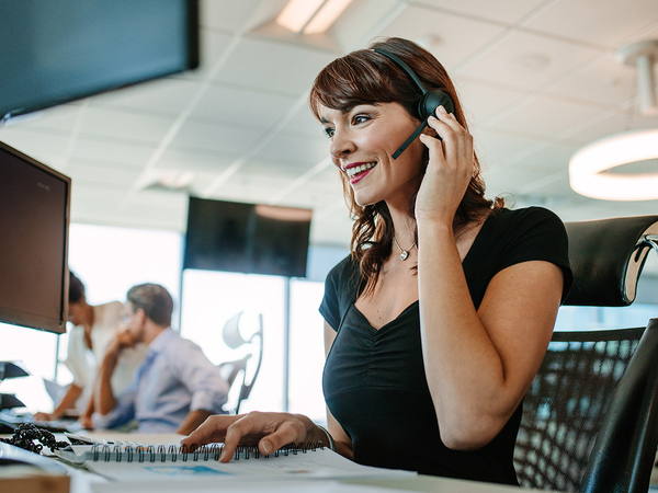 smiling customer service rep speaking to client through headset