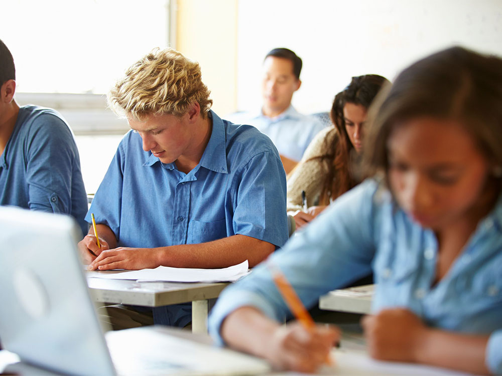 group of students taking notes and on laptops