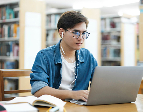 male student on laptop in library