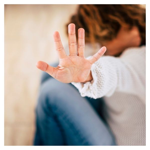 woman cowering with hand up