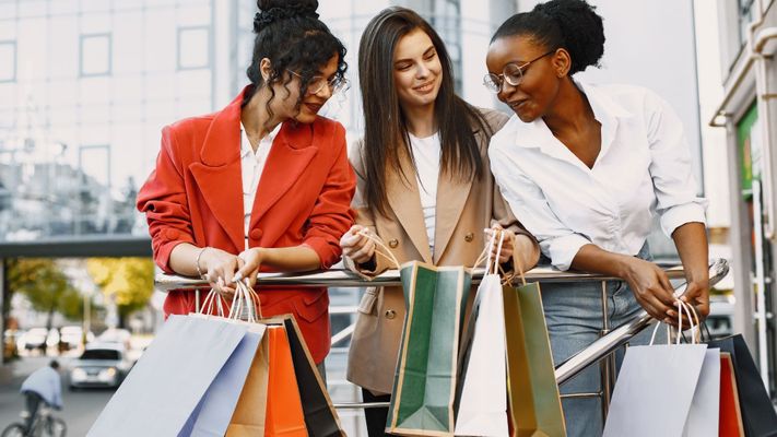women looking in shopping bag of friend and smiling