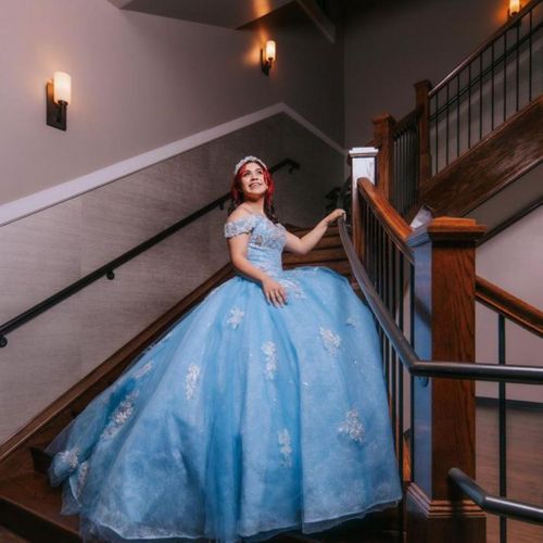 woman in large, elegant blue dress ascending stairs