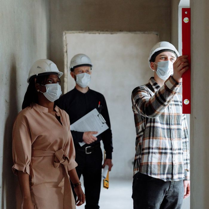 3 people inspecting a wall while they have protective masks on 3 people inspecting a wall while they have protective masks on