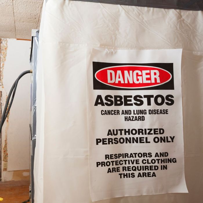 a sign taped to a wall that reads "danger, asbestos..."