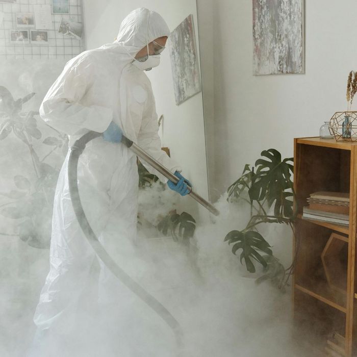 a person in a full hazmat suit with a mask spraying for asbestos in a home a person in a full hazmat suit with a mask spraying for asbestos in a home