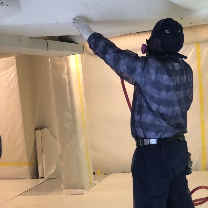 a man inspecting a wall during an asbestos abatement service a man inspecting a wall during an asbestos abatement service