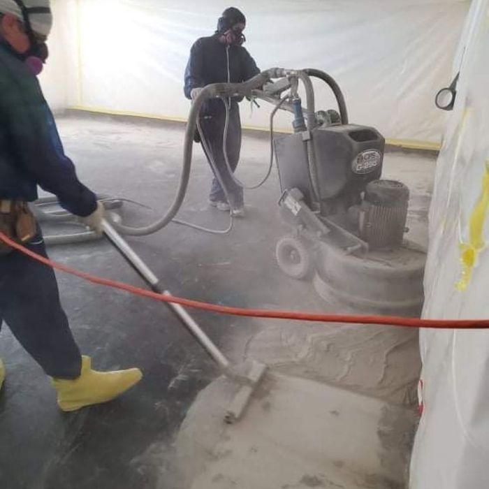 workers sanding a floor as they prep to re-seal it after an asbestos abatement service workers sanding a floor as they prep to re-seal it after an asbestos abatement service