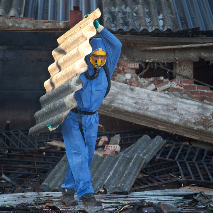 A man removing a piece of metal with asbestos on it