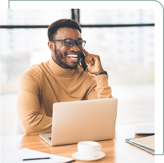 man on a phone call laughing while using a laptop