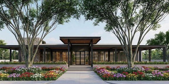 Wide landscape shot of modern restaurant exterior with large trees and flower beds.